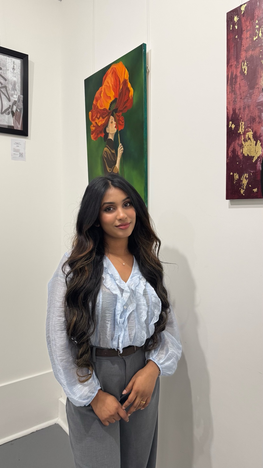 Shehara standing in front of her Bloom painting at a gallery exhibition